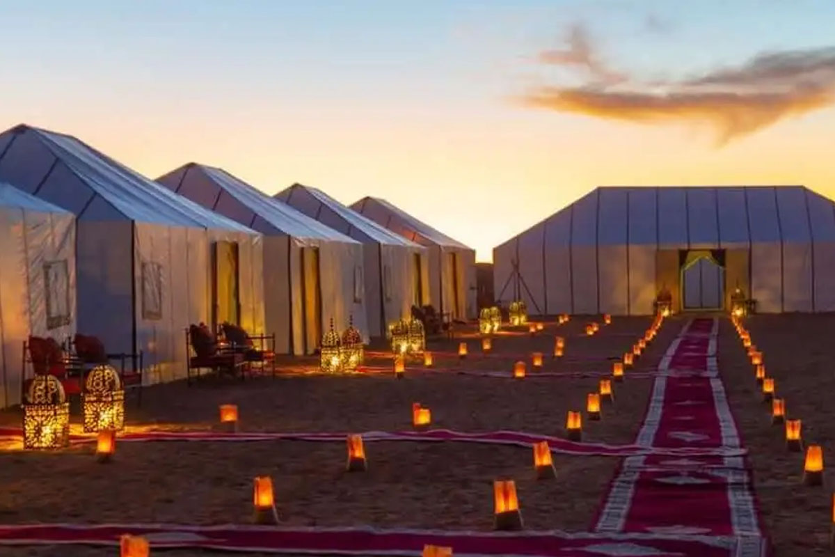 A luxury desert camp tent in the Sahara Desert at dusk.